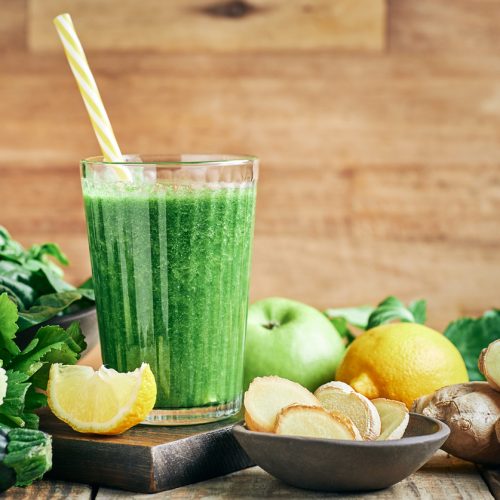 Smoothie frais et sain aux légumes verts et au gingembre, servi dans un verre avec du citron pour des cheveux resplendissants.